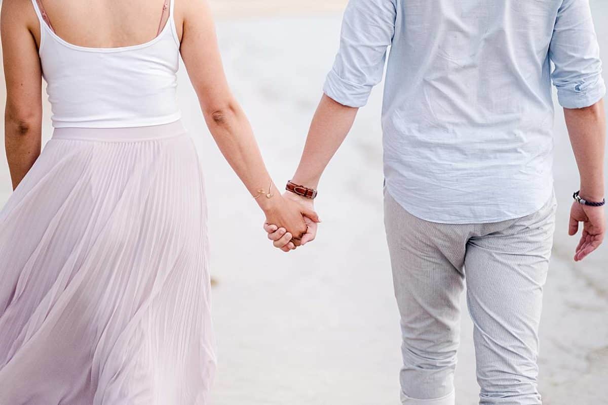 seance couple sur le bassin d'Arcachon ou l'on voit le détails des mains sur un couple en train de marcher au bord de l'eau avec des photos réalisé par un photographe professionnel