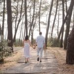 seance couple ou les futurs mariés marchent de dos avec une vue sur le bassin d'arcachon en pleine foret