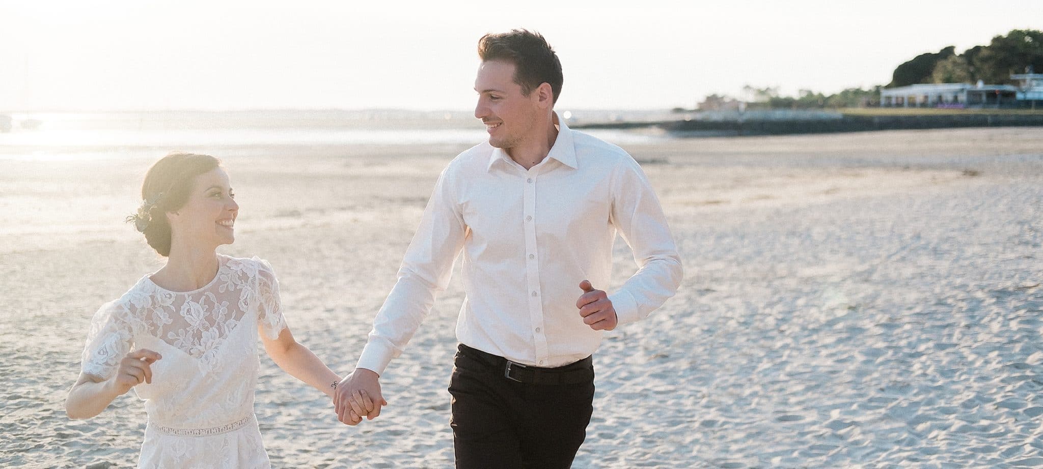 seance couple au bord ou les futurs mariés sont en train de courir sur le sable au bord du bassin d'arcachon les pieds dans l'eau a andernos les bains