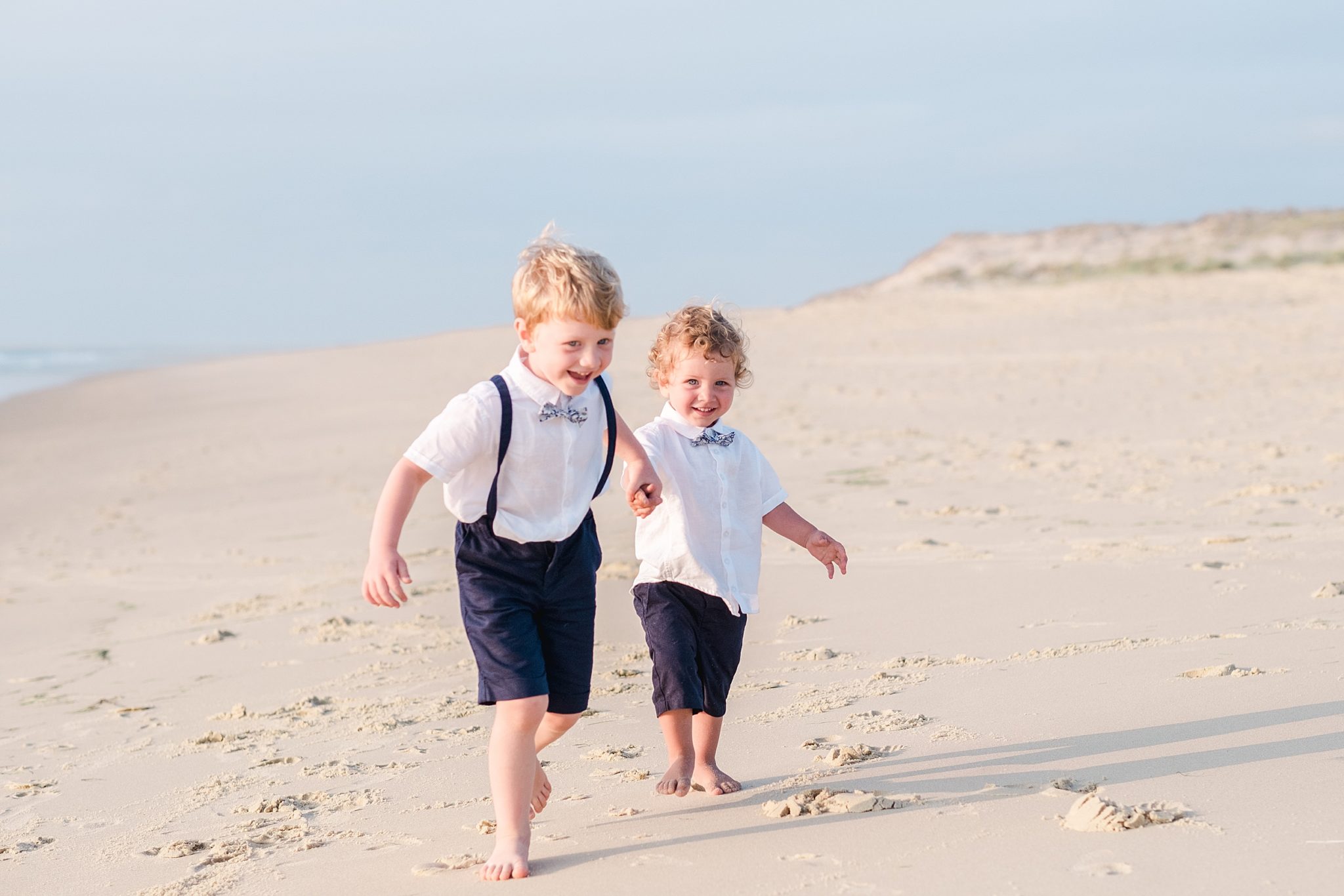 des enfants courent au bord de l'ocean lors d'une séance photo de famille au bord de l'océan