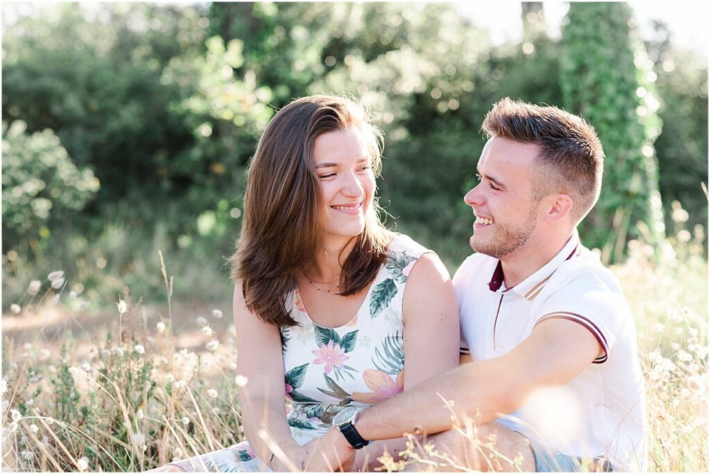 shooting photo par un photographe de bordeaux ou le couple est assis dans l'herbe en train de passer un bon moment ensemble