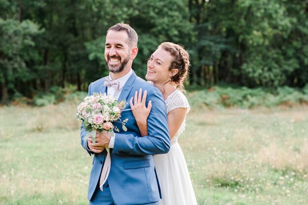 seance couple de mariage en pleine nature avec le marié qui tient le bouquet de fleurs