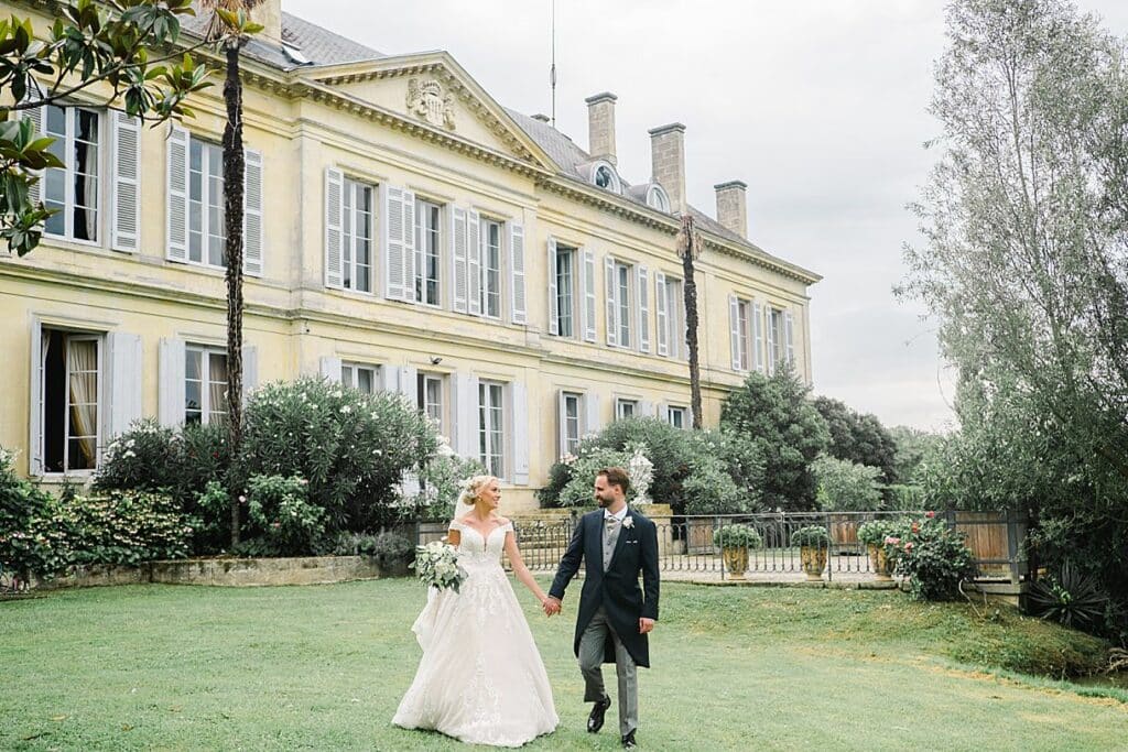 Les mariés marchent en se regardant avec un château en arrière plan