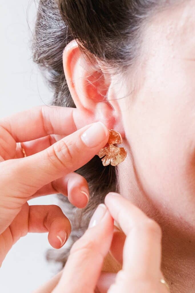 détail de la mise en place de la boucle d'oreille sur la mariée