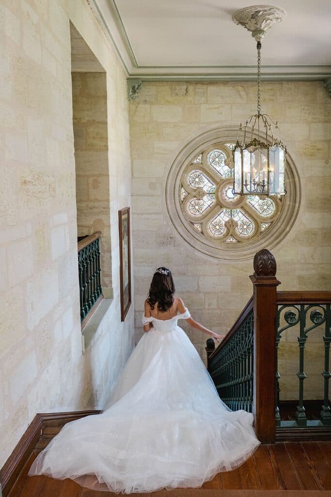 la mariée est en train de descendre les escaliers avec sa belle robe au château pape clement