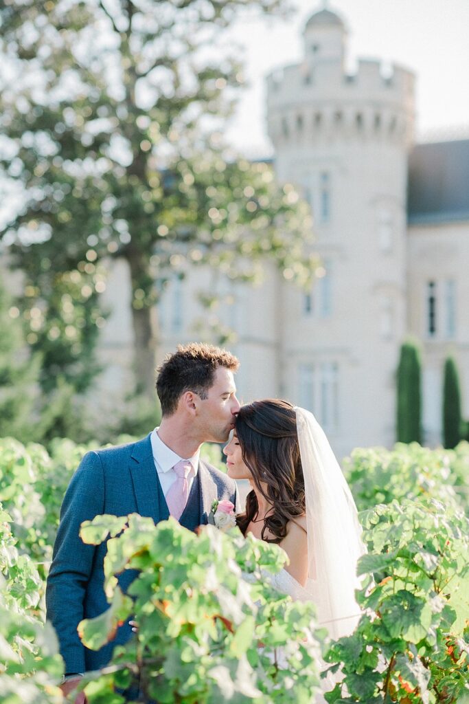 séance des mariés dans les vignes avec en arrière plan le château pape clément