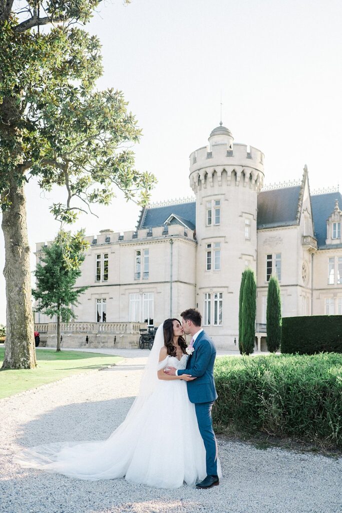 les mariés sont en train de s'embrasser devant le château pape clément