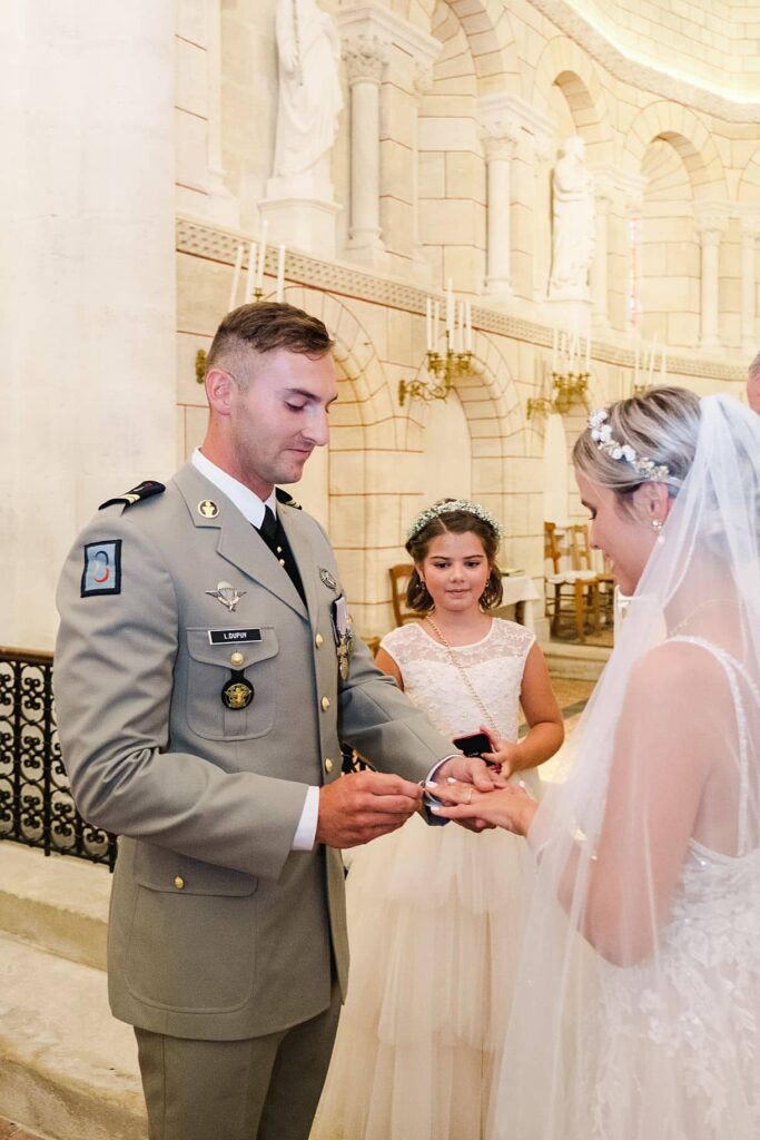 le marié met la bague à la mariée à l'église