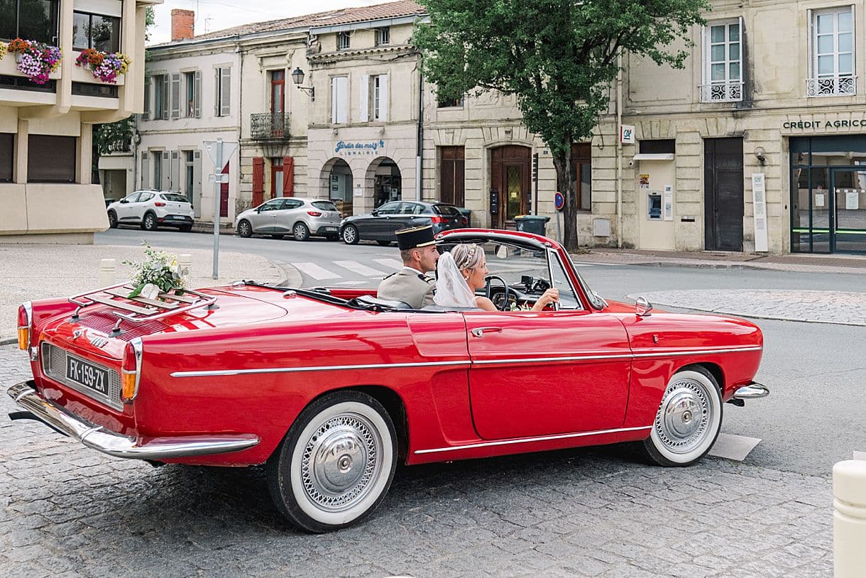 les mariés sortent de l'église avec leur voiture de collection pour se rendre au chateau de birot