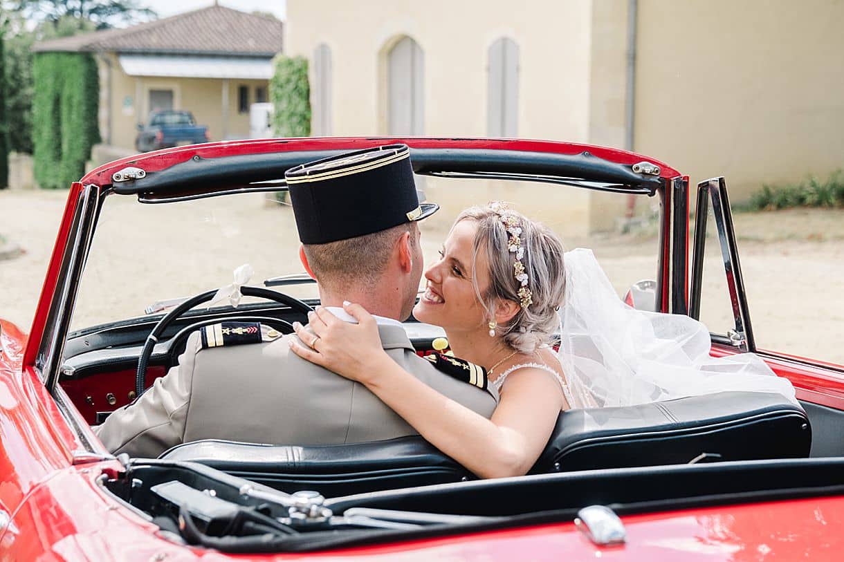la mariée embrasse son mari dans la voiture de collection au chateau de birot