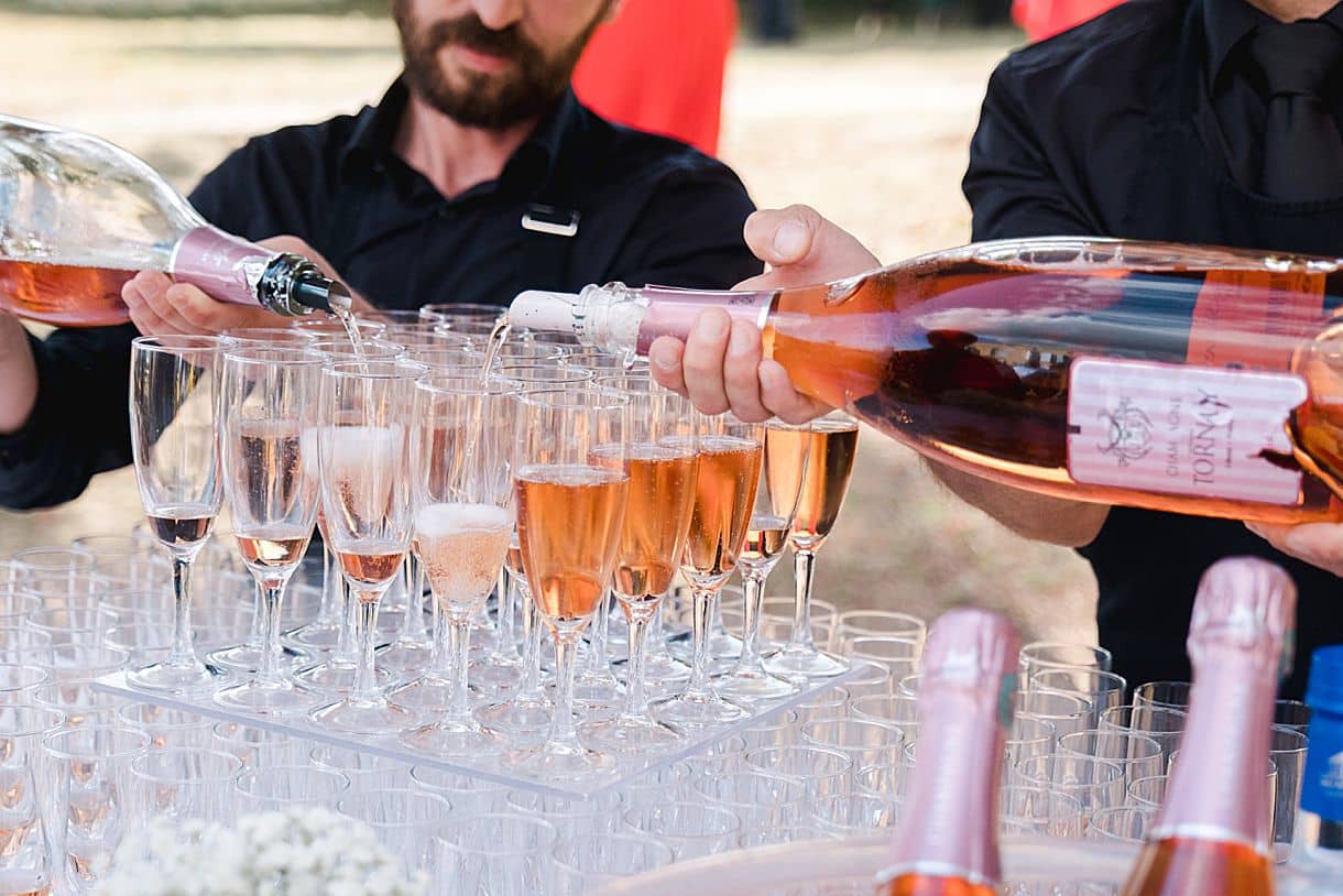 le traiteur dulou sert le champagne dans les verres lors du cocktail des mariés