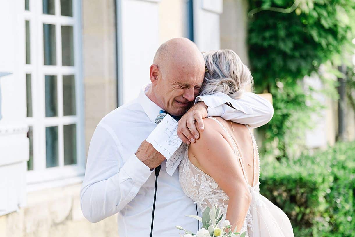 le papa de la mariée et la mariée se prennent dans les bras et pleure pendant le discour au chateau de birot