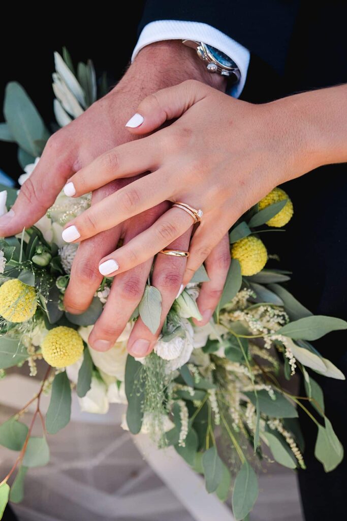 photos de détails des alliances des mariés sur le bouquet de fleurs