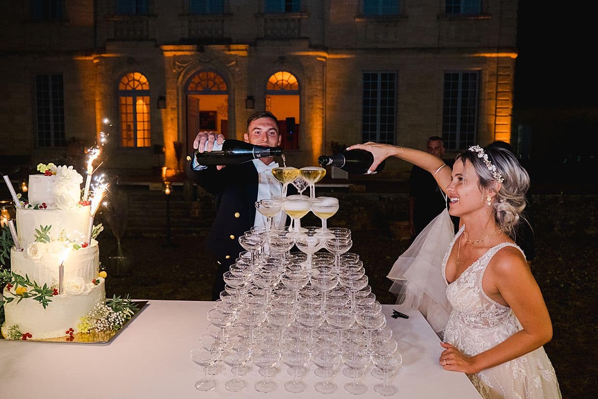 les mariés sont en train de verser le champagne dans la fontaine à champagne au chateau de birot