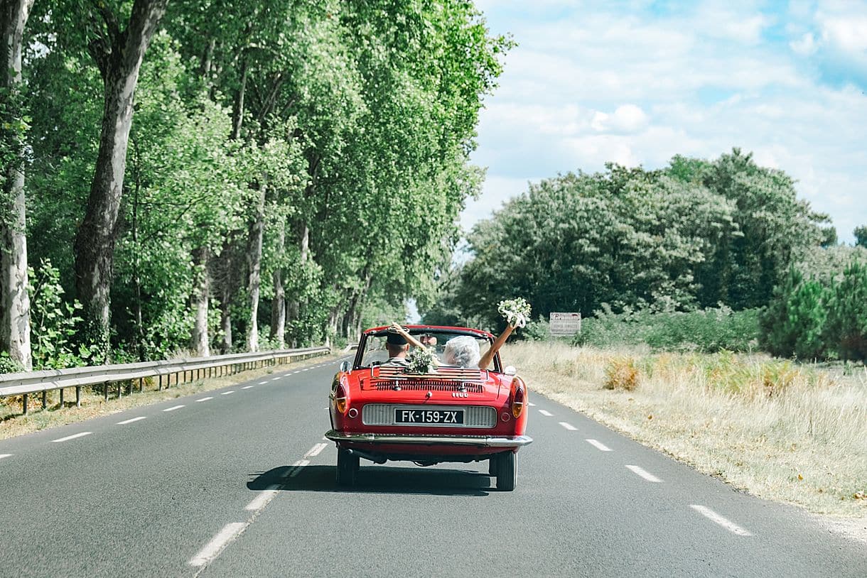 les mariés sont en route pour le chateau de birot proche de bordeaux et elle lève son bouquet de fleurs