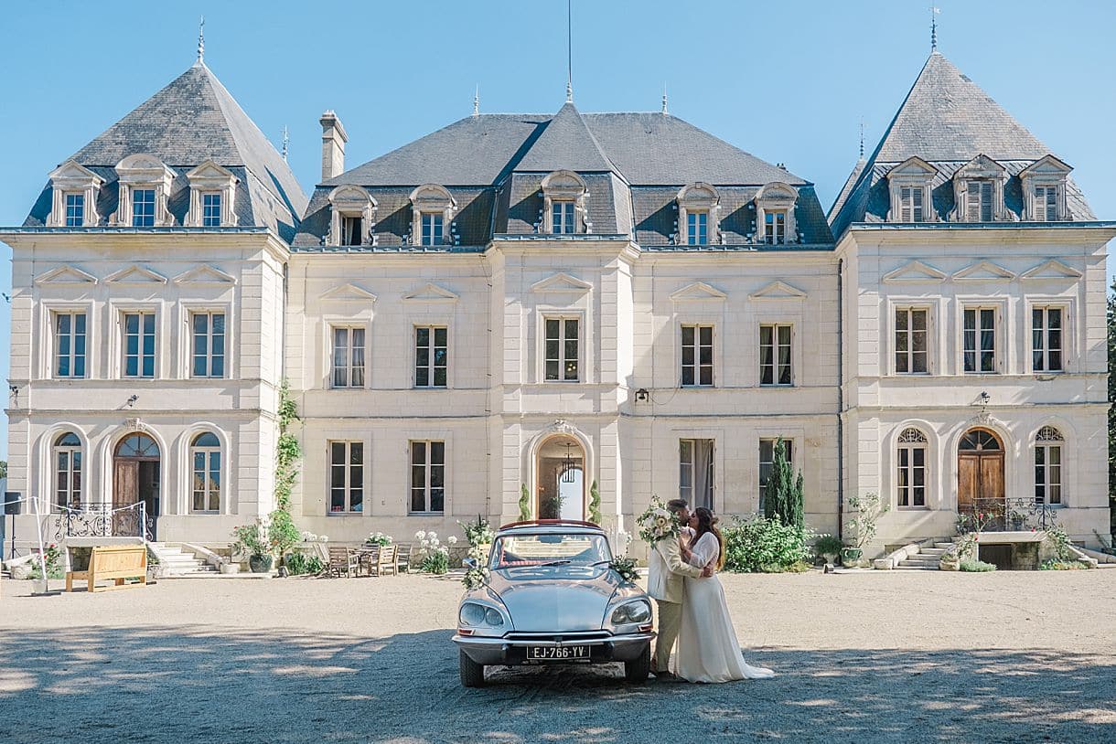 les mariés s'embrassent avec leur DS au chateau fengari à clairac