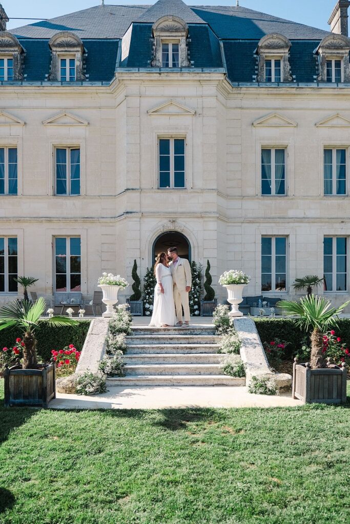 les mariés s'embrassent sur les marches du chateau fengari proche de bordeaux