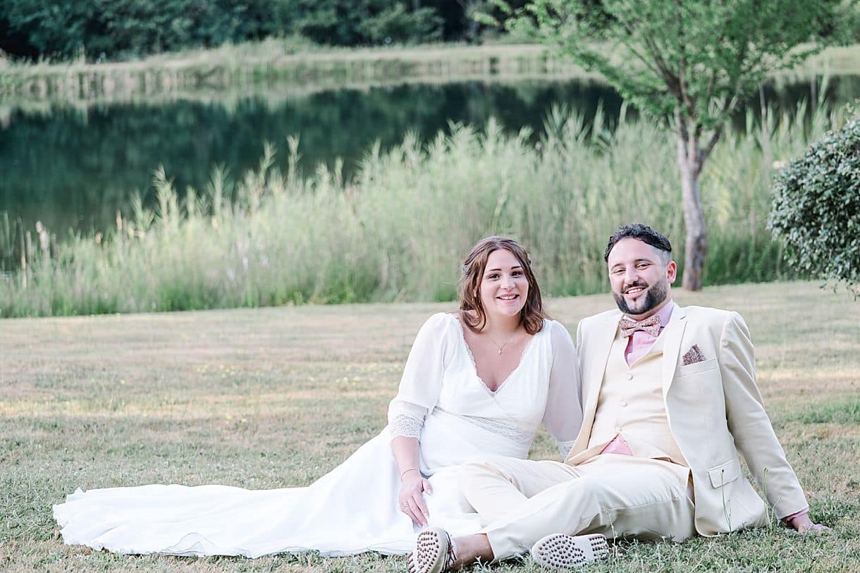 les mariés sont assis sur l'herbe proche du lac du chateau fengari proche de bordeaux