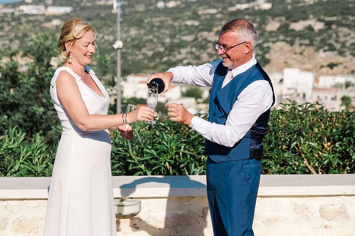les mariés sont en train de boire une coupe de champagne ensemble lors de leur mariage en crete
