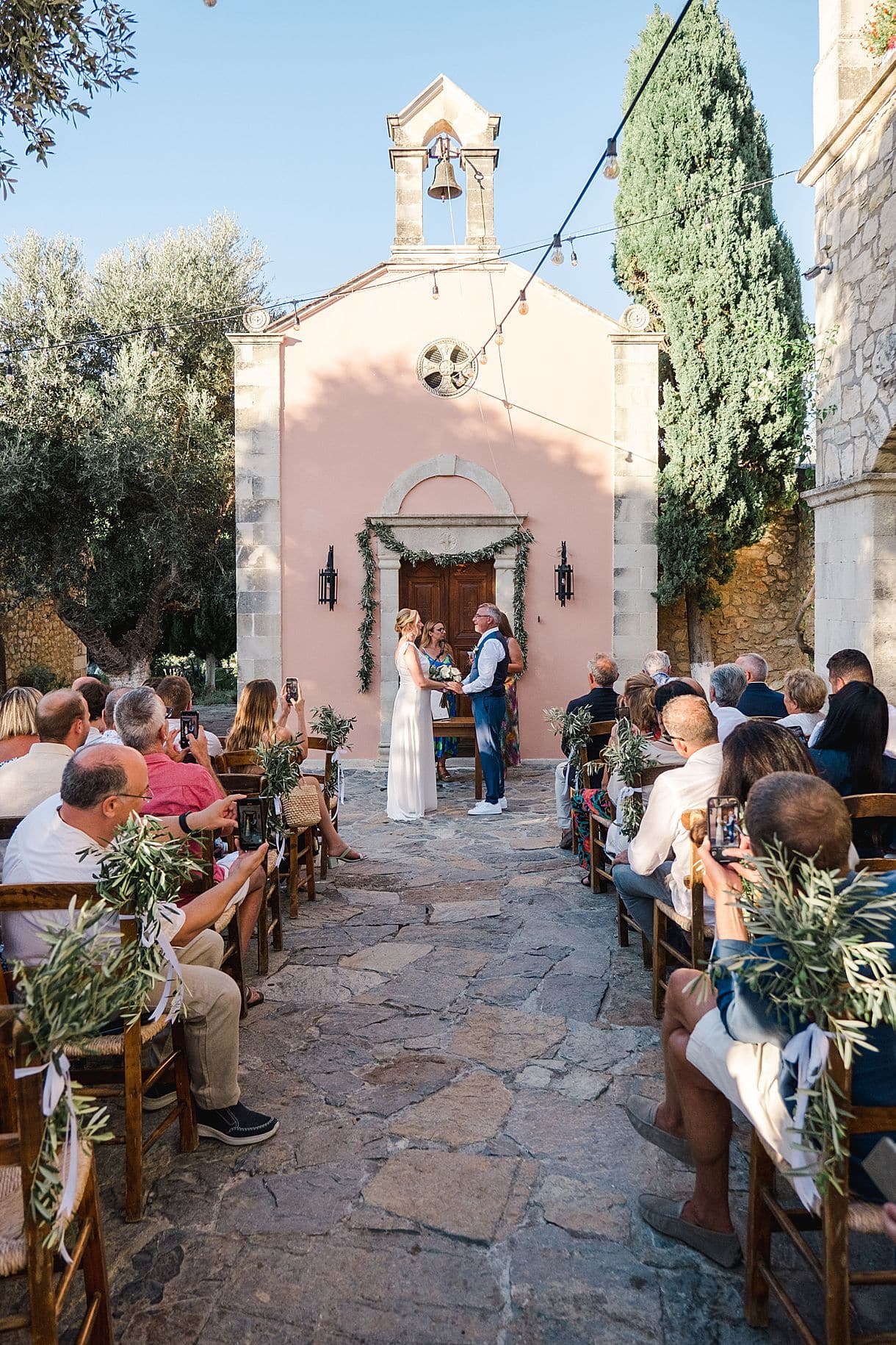 les mariés sont devant l'église lors de leur cérémonie laïque à l'agrecofarms en crete