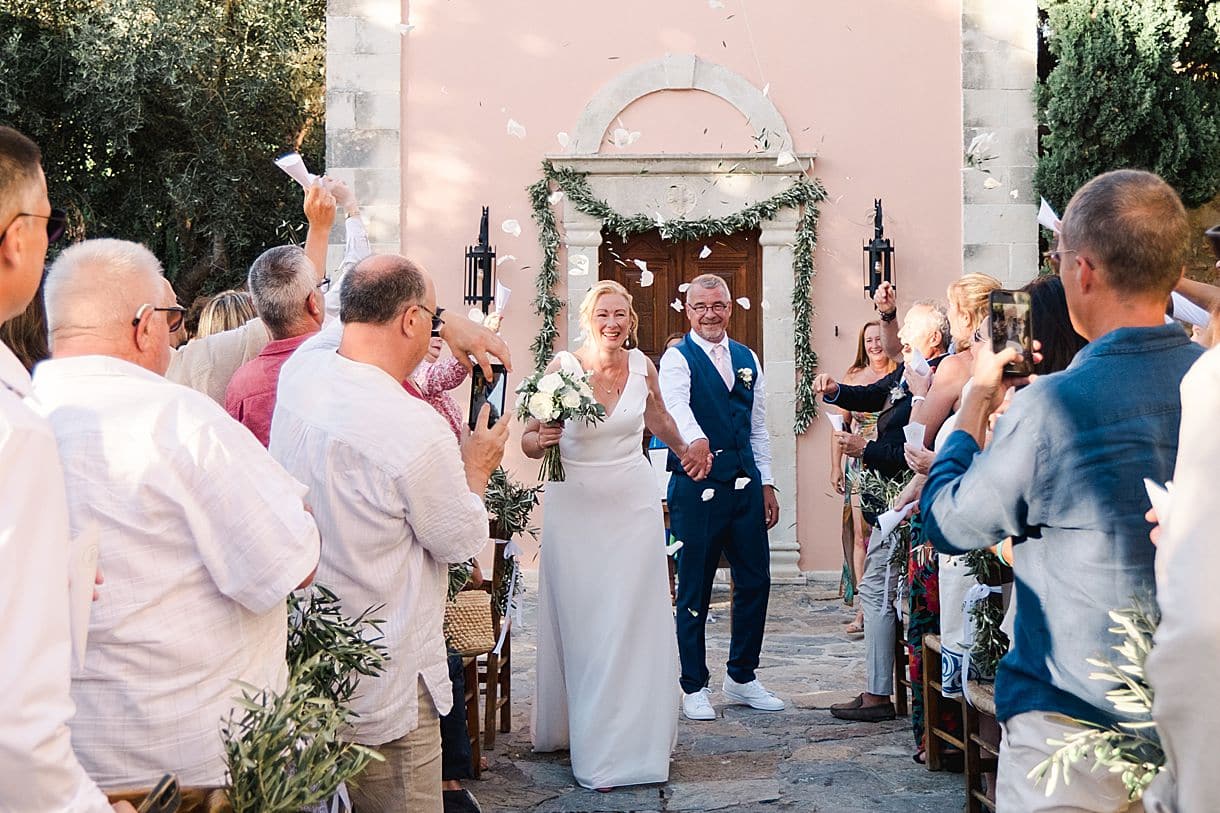 lors du mariage à l'agrecofarms en crete les invités lancent des pétales de fleurs et des feuilles d'olivier sur les mariés