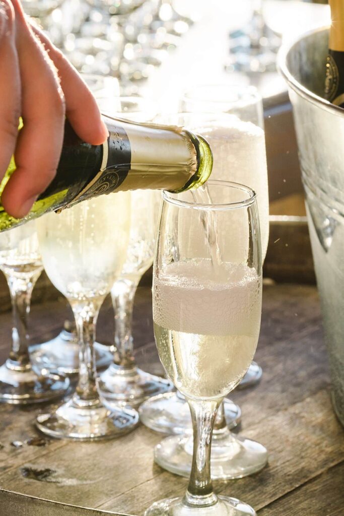 le traiteur est en train de remplir une coupe de champagne pendant le mariage de bernadette et françois à l'agrecofarms en crete