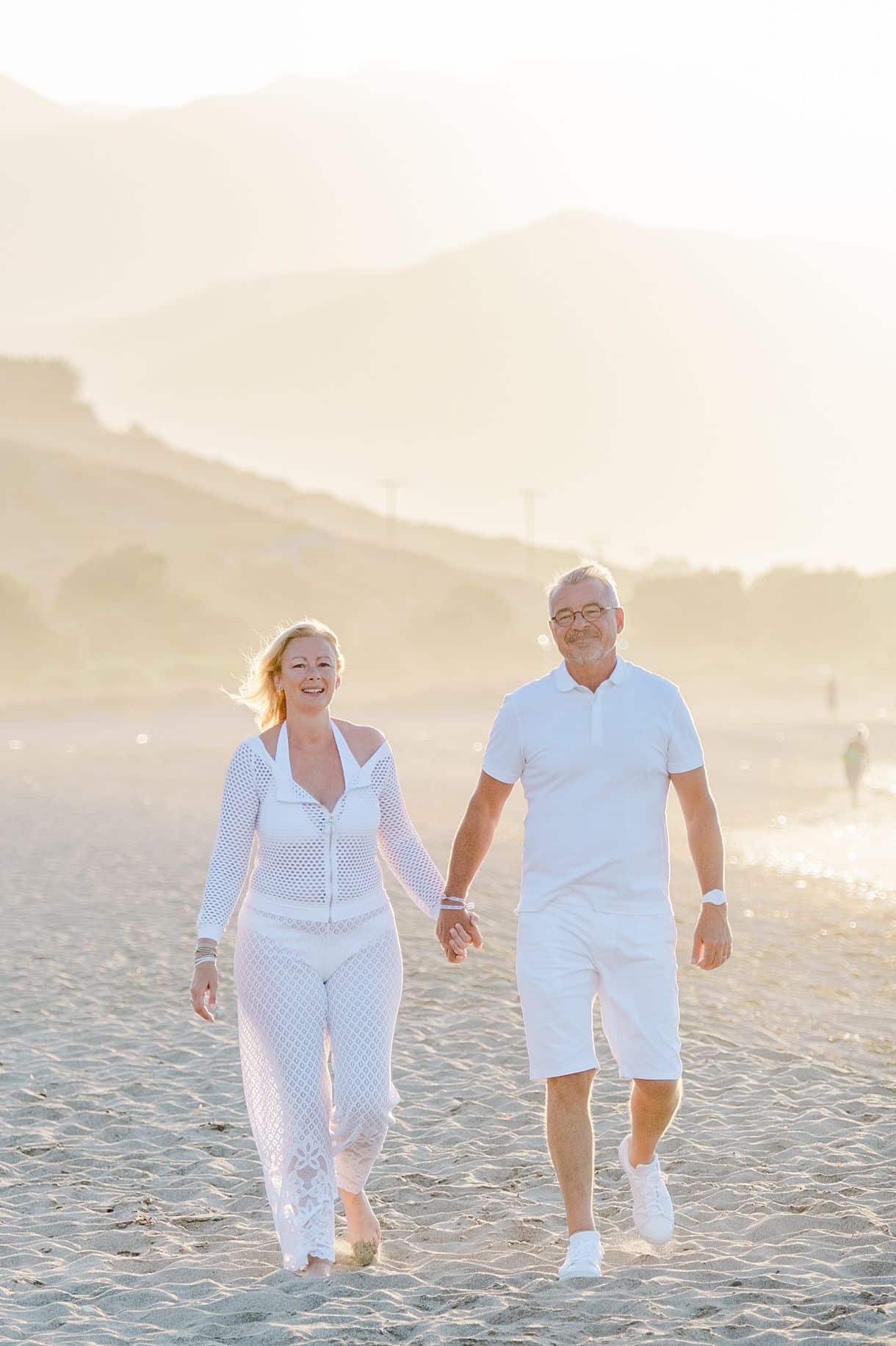 les mariés marchent dans le sable sur une plage en crête pour leur photos de couple