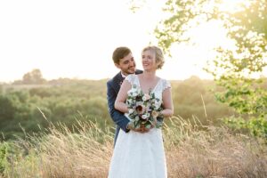 photos de couple sur un coucher de soleil avec de très belle fleurs ou les mariés sourit. L'article parle de prévoir un budget de mariage pour son photographe de mariage a Bordeaux